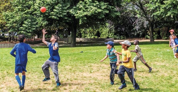 enfants jouent au ballon dans un parc
