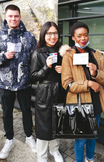 Trois jeunes tenant une carte d'électeur
